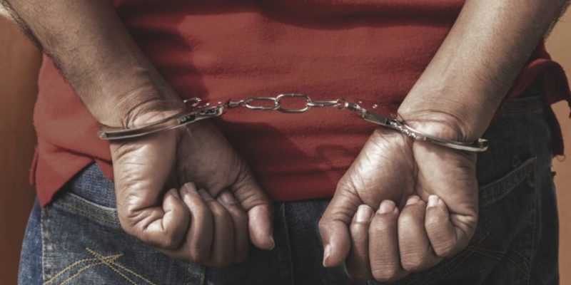 a young person's hands balled into fists, shackled in handcuffs