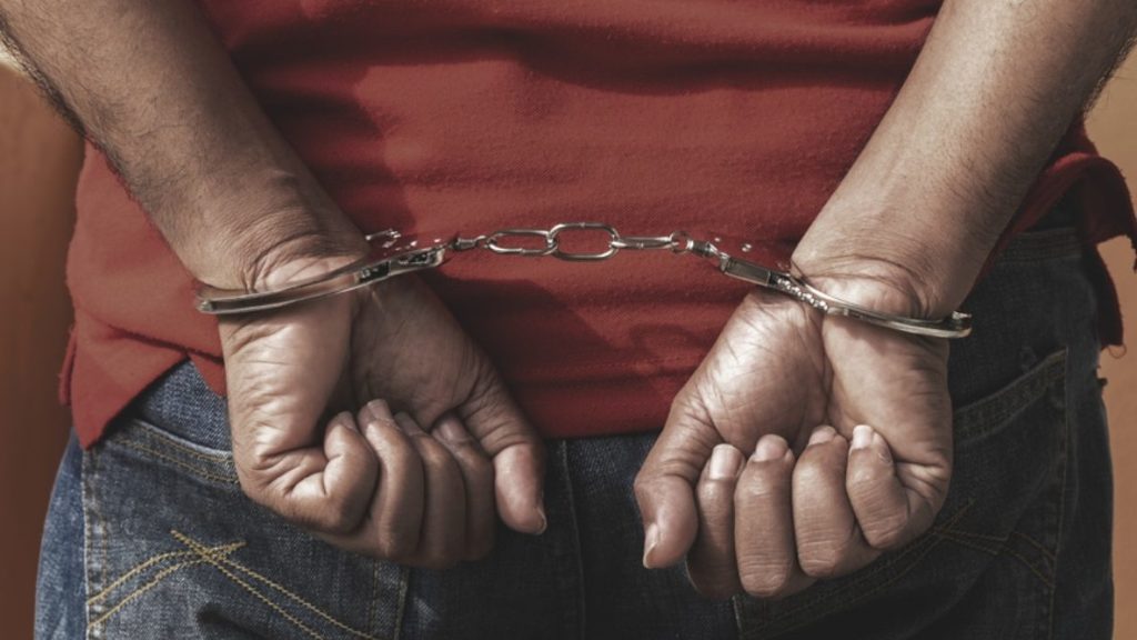 a young person's hands balled into fists, shackled in handcuffs